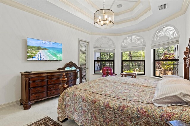 bedroom with ornamental molding, an inviting chandelier, light colored carpet, and a tray ceiling