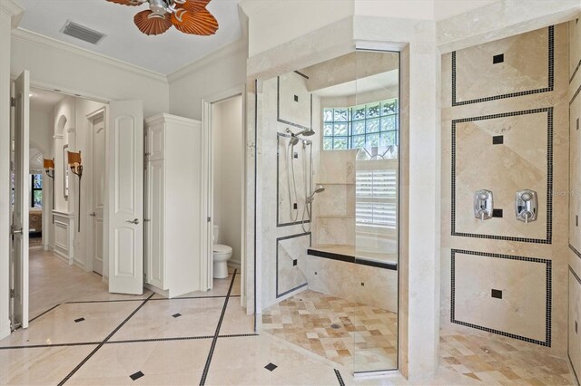 bathroom featuring a tile shower, crown molding, tile patterned floors, toilet, and ceiling fan