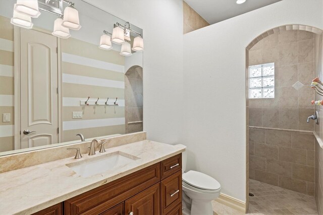 bathroom featuring vanity, toilet, and a tile shower