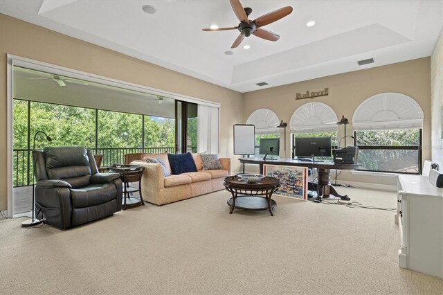 carpeted living room featuring ceiling fan and a tray ceiling