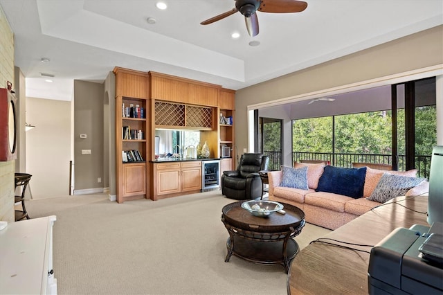 living room featuring ceiling fan, a tray ceiling, carpet, and wine cooler