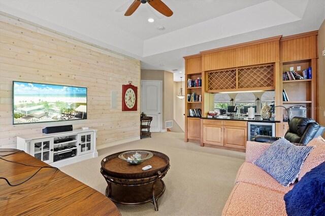 living room featuring wood walls, ceiling fan, and light colored carpet