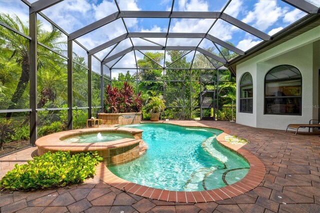 view of pool with an in ground hot tub, a patio, pool water feature, and glass enclosure