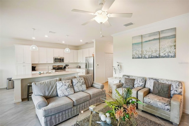 living area with crown molding, visible vents, a ceiling fan, light tile patterned flooring, and baseboards