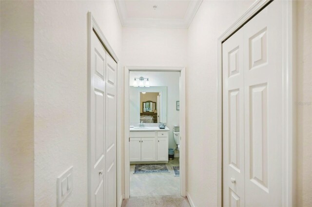 hall with a sink and crown molding