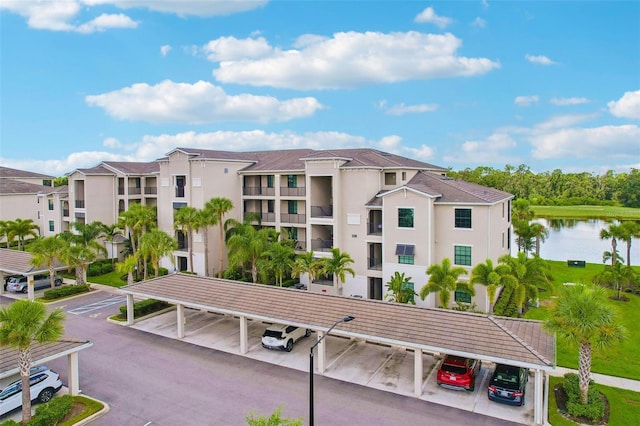 view of building exterior featuring a water view and covered and uncovered parking