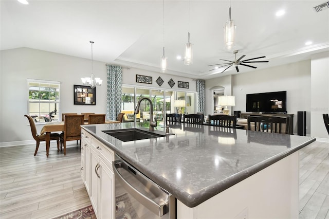 kitchen with sink, white cabinetry, dark stone countertops, stainless steel dishwasher, and a large island with sink