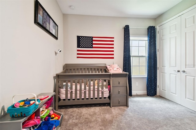 bedroom with a crib, light carpet, and a closet