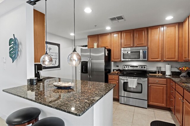 kitchen featuring dark stone countertops, appliances with stainless steel finishes, and kitchen peninsula