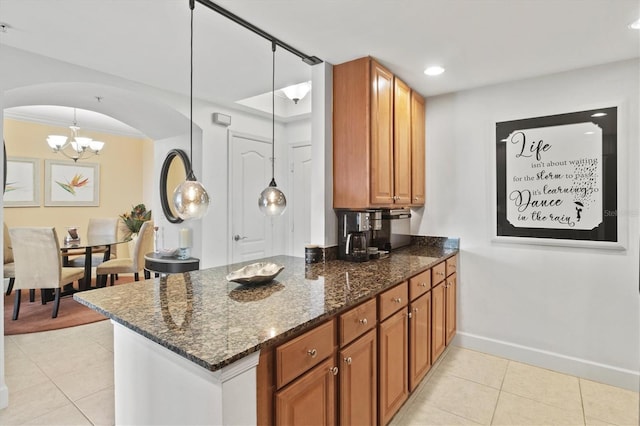 kitchen with light tile patterned floors, a chandelier, hanging light fixtures, dark stone countertops, and kitchen peninsula