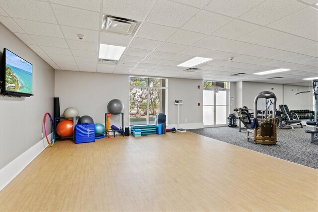 exercise room with light hardwood / wood-style flooring and a paneled ceiling