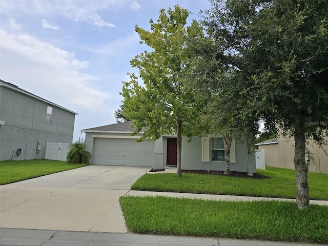 view of property hidden behind natural elements featuring a garage and a front yard