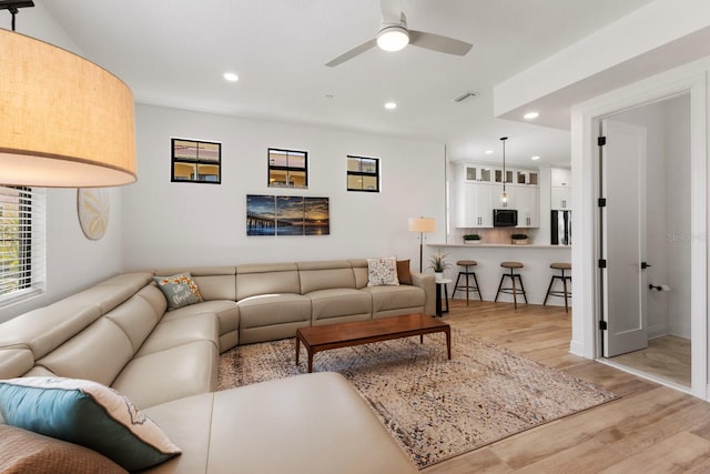 living room with ceiling fan and light hardwood / wood-style flooring