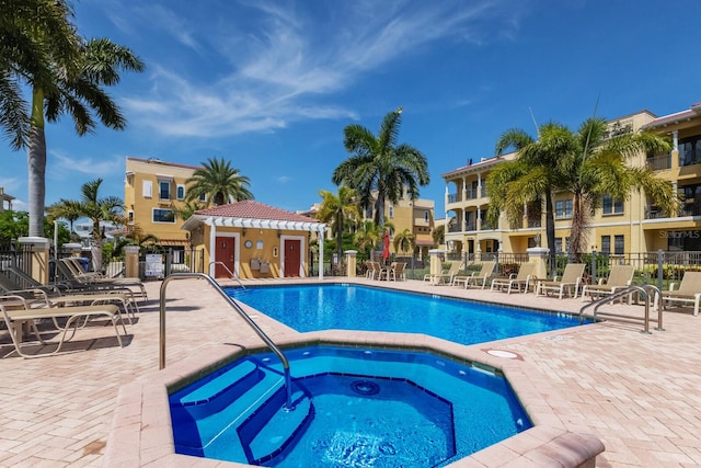 pool with a community hot tub, a patio, and fence