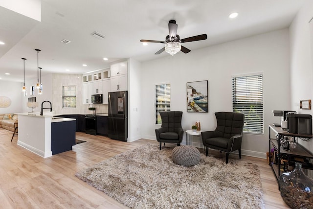 kitchen featuring recessed lighting, white cabinets, light wood-style floors, black appliances, and glass insert cabinets