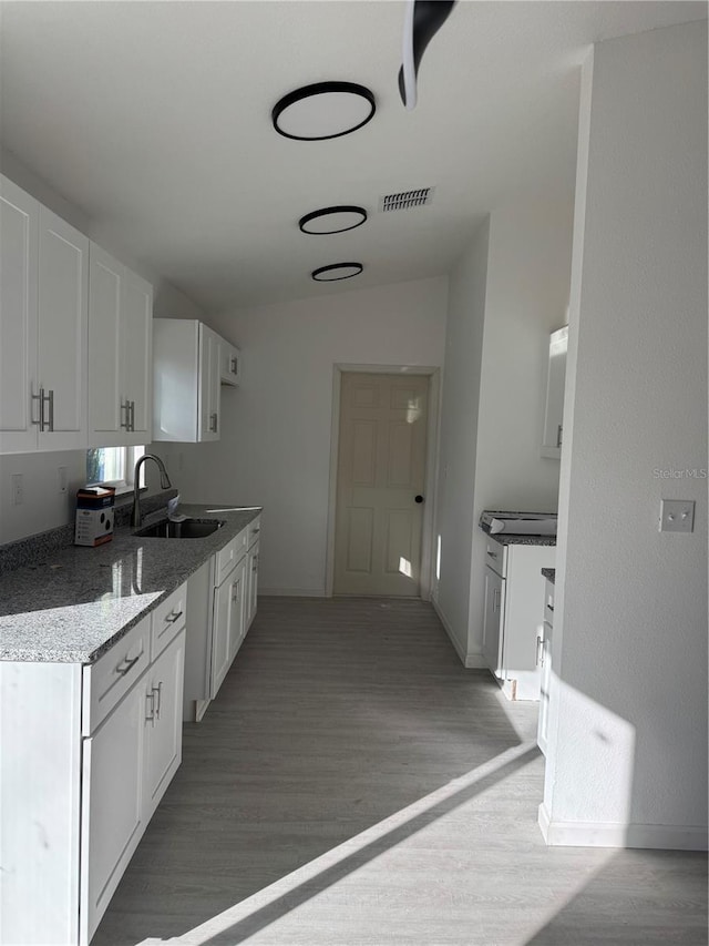 kitchen with white cabinetry, sink, lofted ceiling, and light hardwood / wood-style flooring