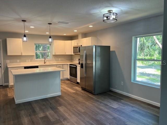 kitchen with stainless steel appliances, hanging light fixtures, a center island, sink, and white cabinetry