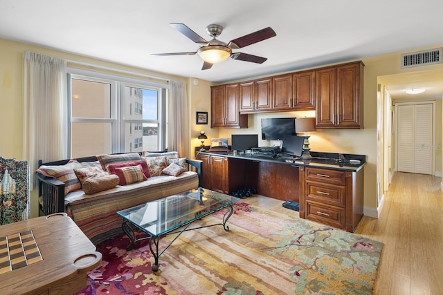 home office with built in desk, light hardwood / wood-style flooring, and ceiling fan