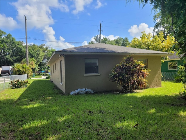 707 13th St W, Palmetto, FL 34221 - view of side of property with a lawn, fence, and stucco siding