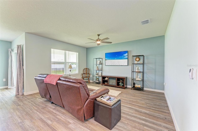 living room with a textured ceiling, ceiling fan, and light hardwood / wood-style floors