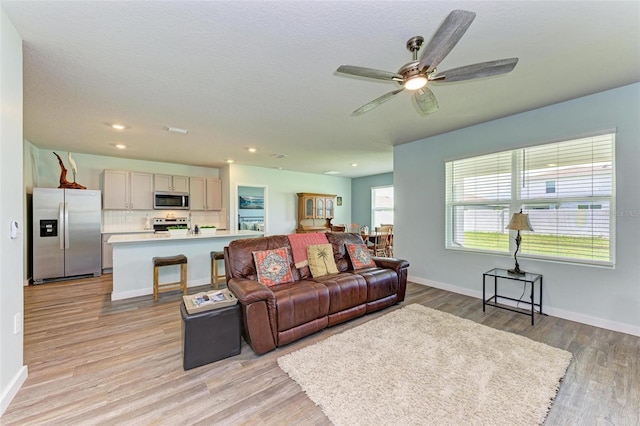 living room featuring light hardwood / wood-style flooring and ceiling fan