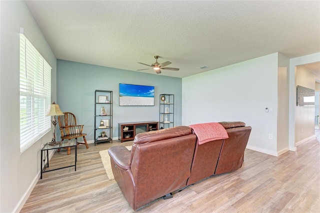 living room featuring a textured ceiling, ceiling fan, and light wood-type flooring