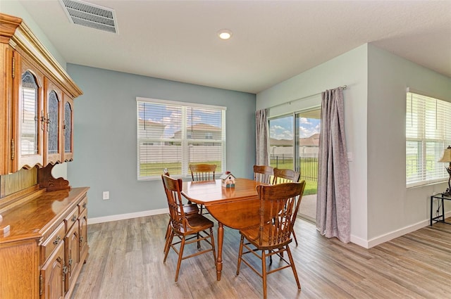 dining room with light hardwood / wood-style flooring and a healthy amount of sunlight