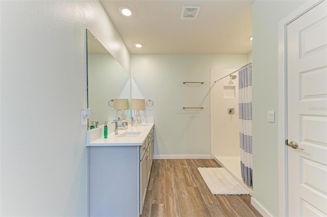 bathroom featuring vanity, walk in shower, and wood-type flooring