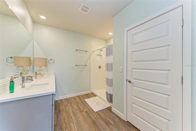 bathroom featuring hardwood / wood-style floors, double sink vanity, and a shower with curtain