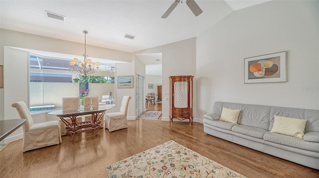 living room featuring ceiling fan with notable chandelier, wood-type flooring, and vaulted ceiling