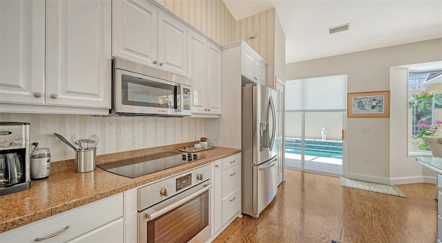 kitchen with light hardwood / wood-style floors, appliances with stainless steel finishes, white cabinetry, and light stone countertops