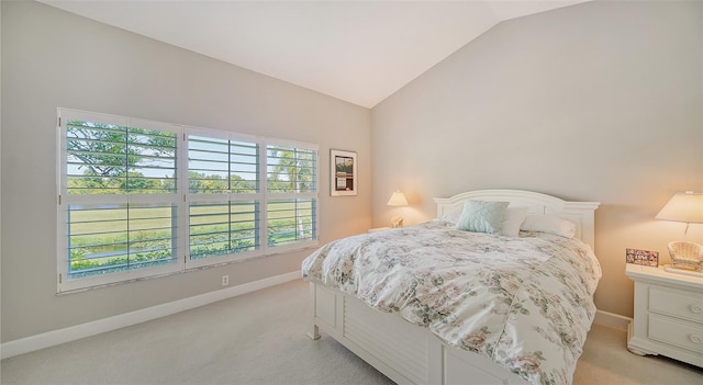 bedroom featuring lofted ceiling, light colored carpet, and multiple windows