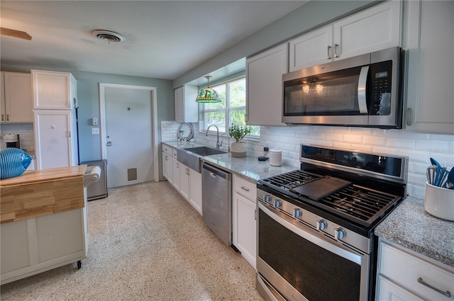 kitchen featuring tasteful backsplash, stainless steel appliances, white cabinets, sink, and light stone countertops