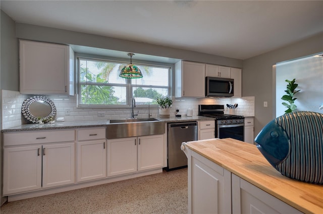 kitchen featuring decorative backsplash, appliances with stainless steel finishes, butcher block counters, and white cabinetry