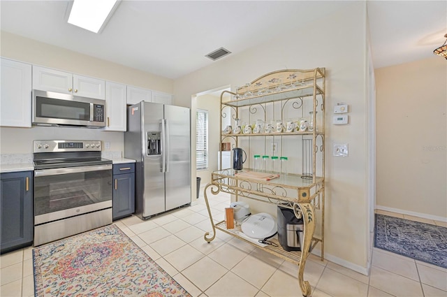 kitchen with white cabinetry, light tile patterned floors, blue cabinetry, and appliances with stainless steel finishes