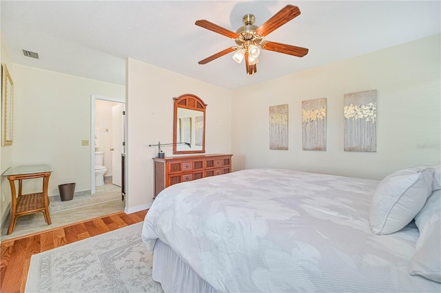 bedroom featuring light hardwood / wood-style floors, ceiling fan, and ensuite bathroom