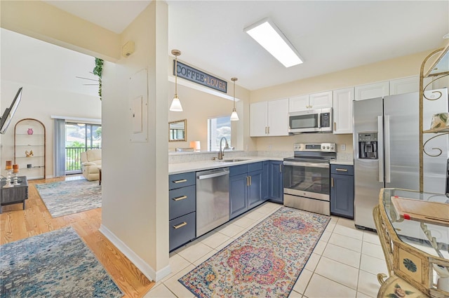 kitchen featuring blue cabinets, sink, white cabinets, hanging light fixtures, and stainless steel appliances