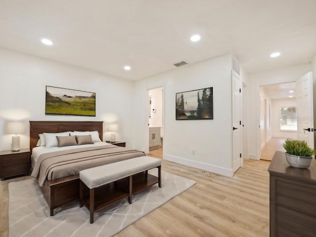 bedroom featuring connected bathroom and light hardwood / wood-style flooring