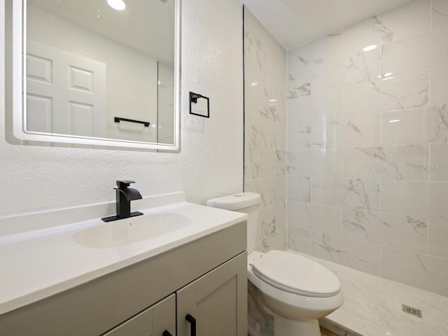 bathroom featuring vanity, toilet, and tiled shower