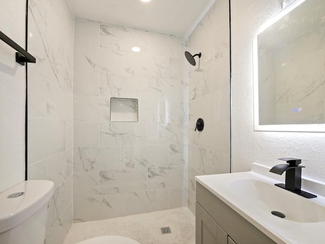 bathroom with vanity, tiled shower, and toilet