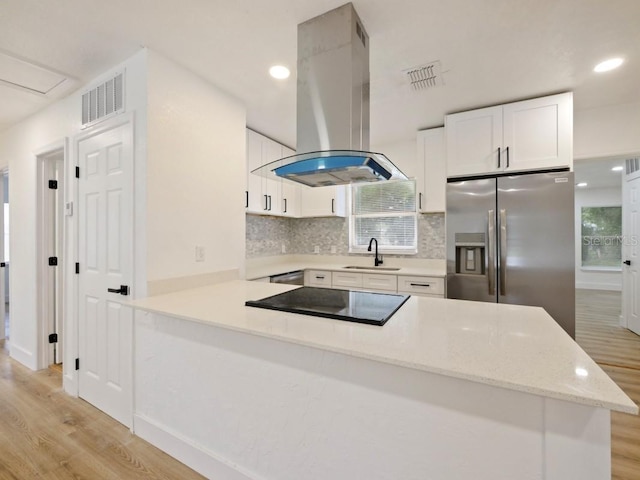 kitchen featuring sink, white cabinets, stainless steel fridge, island exhaust hood, and kitchen peninsula