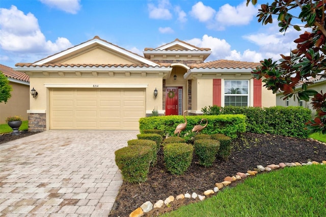 mediterranean / spanish home with a garage, a tile roof, stone siding, decorative driveway, and stucco siding