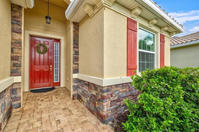 view of exterior entry with stone siding and stucco siding