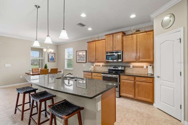 kitchen featuring brown cabinets, a center island with sink, visible vents, appliances with stainless steel finishes, and a sink