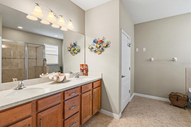 bathroom featuring double vanity, a stall shower, baseboards, and a sink