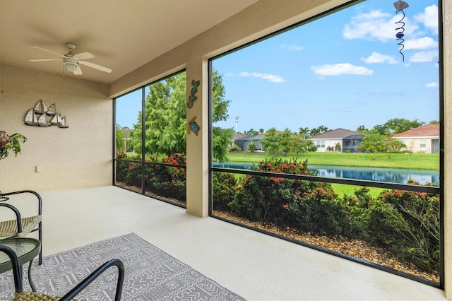 sunroom with a water view, ceiling fan, and a residential view