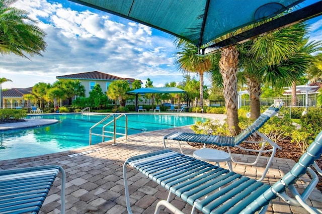 community pool with a patio area and fence