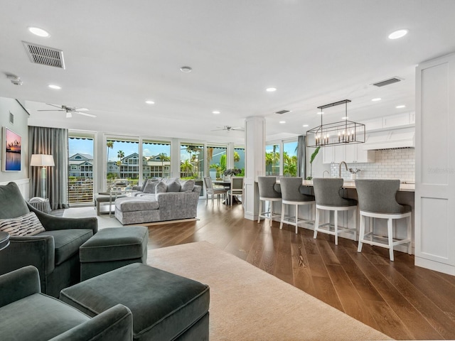 living room with dark hardwood / wood-style flooring, a wealth of natural light, and ceiling fan