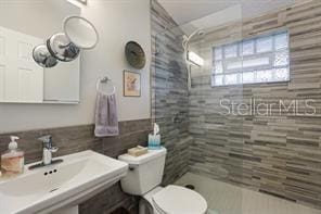 bathroom with sink, toilet, and tiled shower