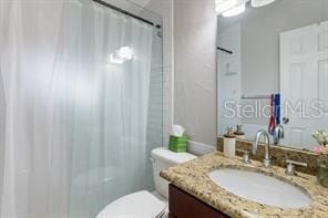 bathroom with toilet, vanity, and walk in shower